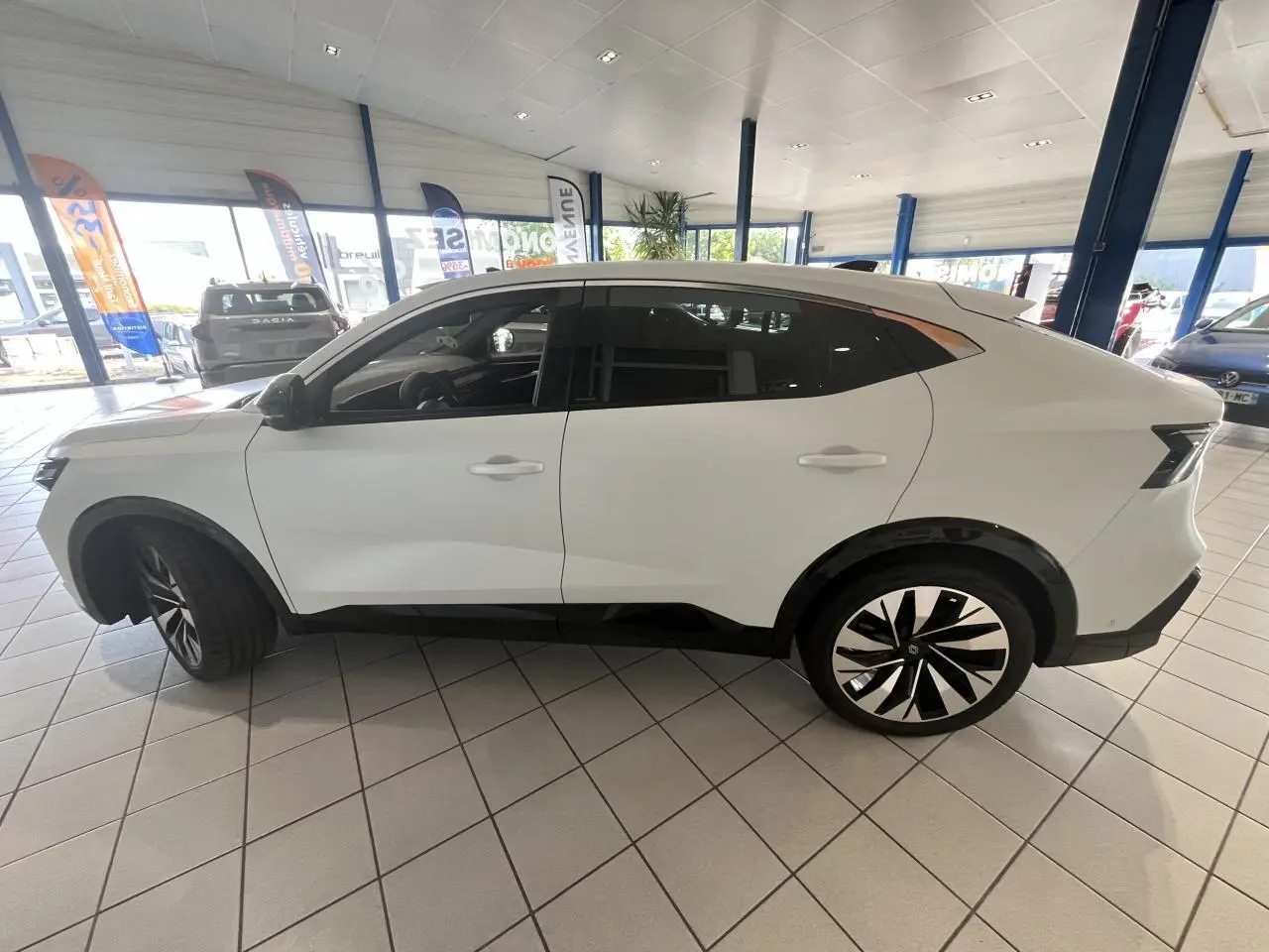 Profil côté gauche du Renault Rafale blanc 2025 en hybride, avec jantes alliage noires et détails noirs contrastants.