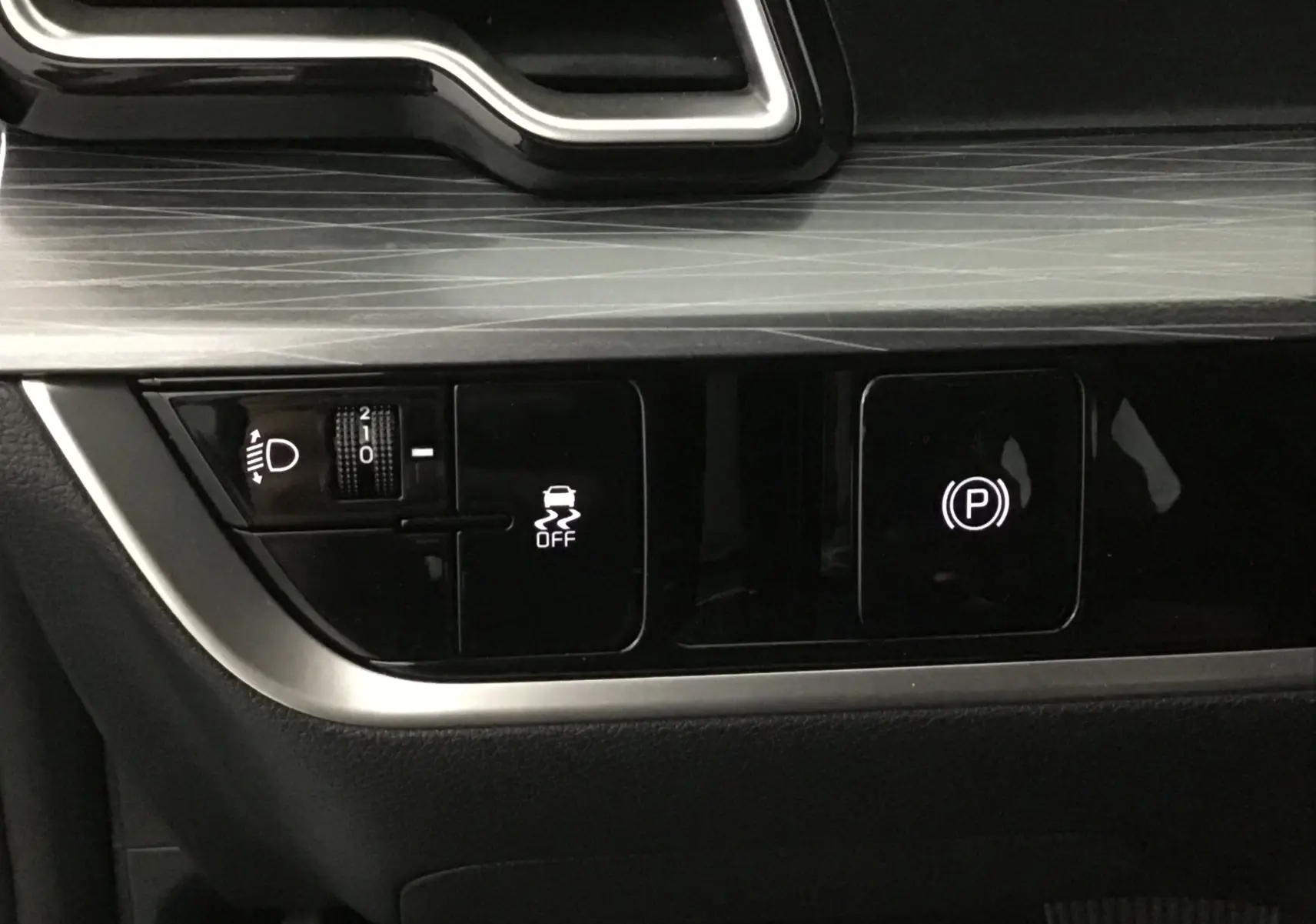 Gros plan sur les commandes d'assistance et frein à main électronique du Kia Sportage gris Sirius 2025.