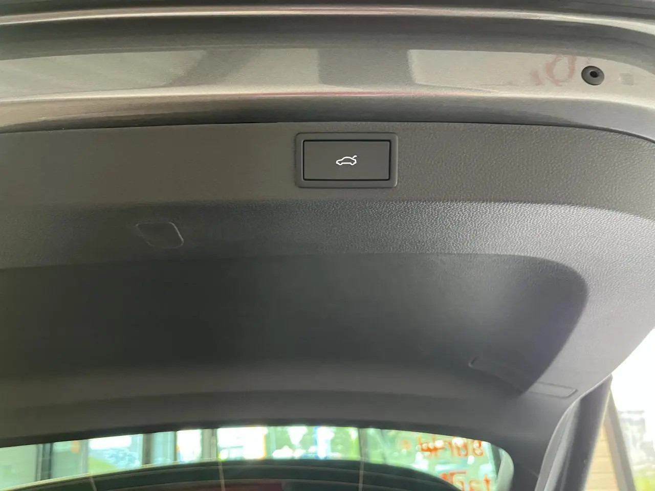 Bouton d'ouverture électrique du hayon sur la face intérieure du coffre d'un SUV SKODA KAROQ gris.