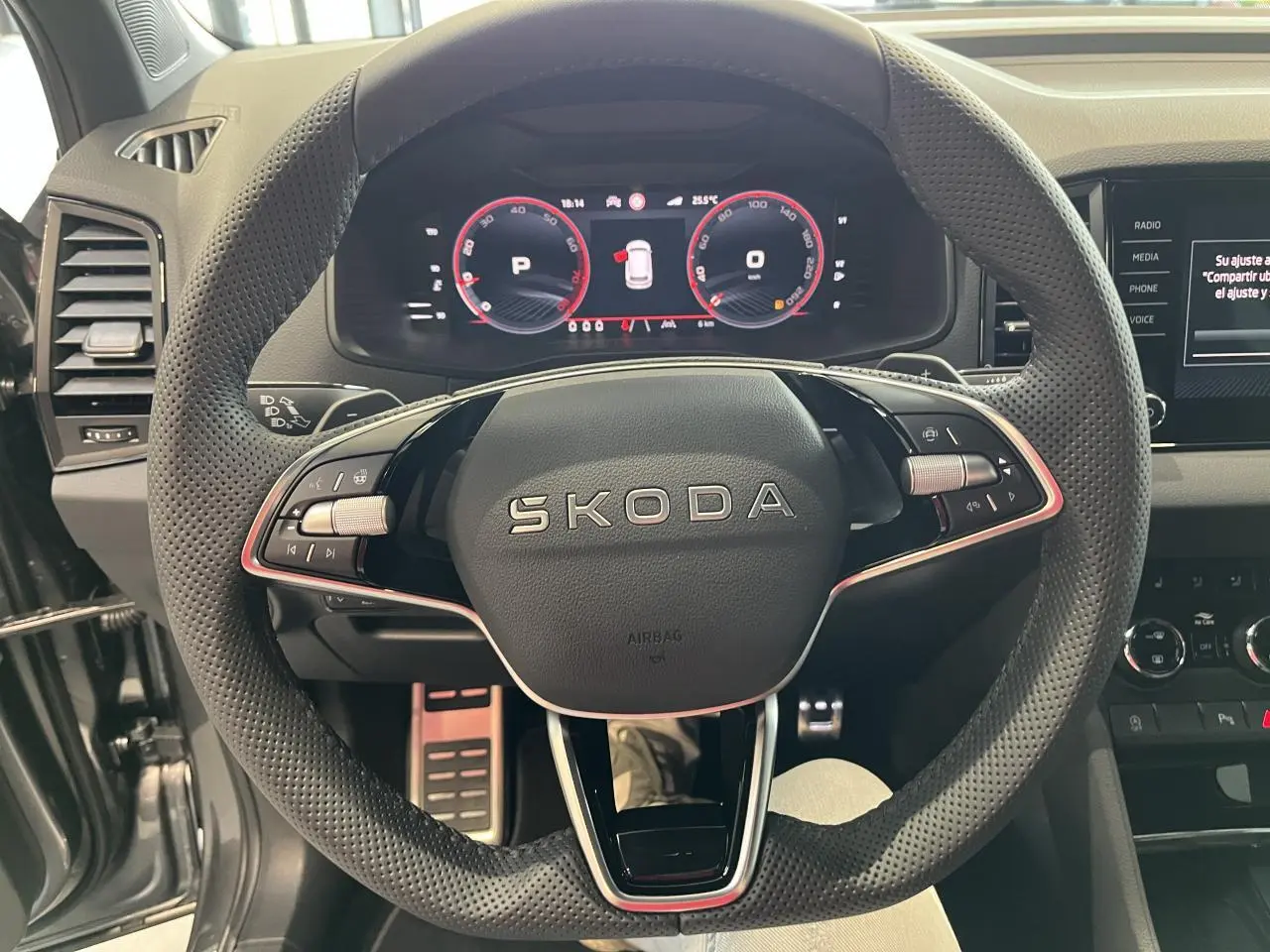 Vue rapprochée du volant perforé noir SKODA KAROQ 2025 avec tableau de bord digital rouge et noir.