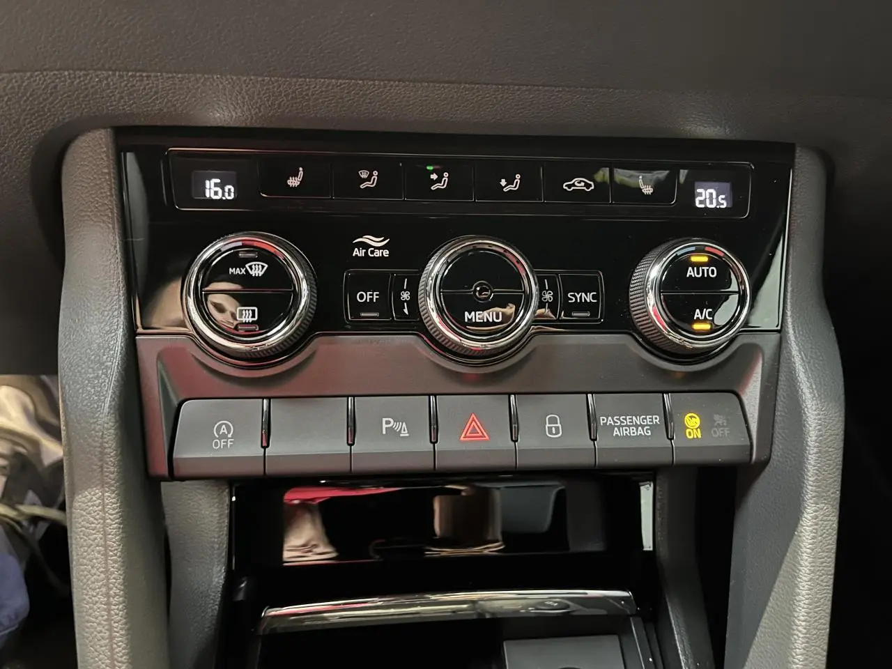 Gros plan sur la console centrale noire du Skoda Karoq gris, avec commandes climatisation automatique tri-zone et boutons fonctionnels.