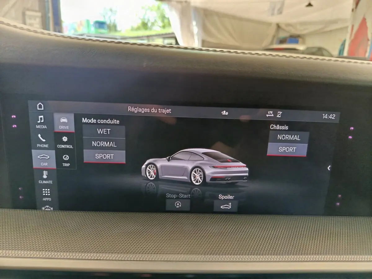 Écran tactile intérieur affichant les réglages de conduite d’une Porsche 911 Carrera 4S Coupé gris foncé en vue 3/4 arrière.