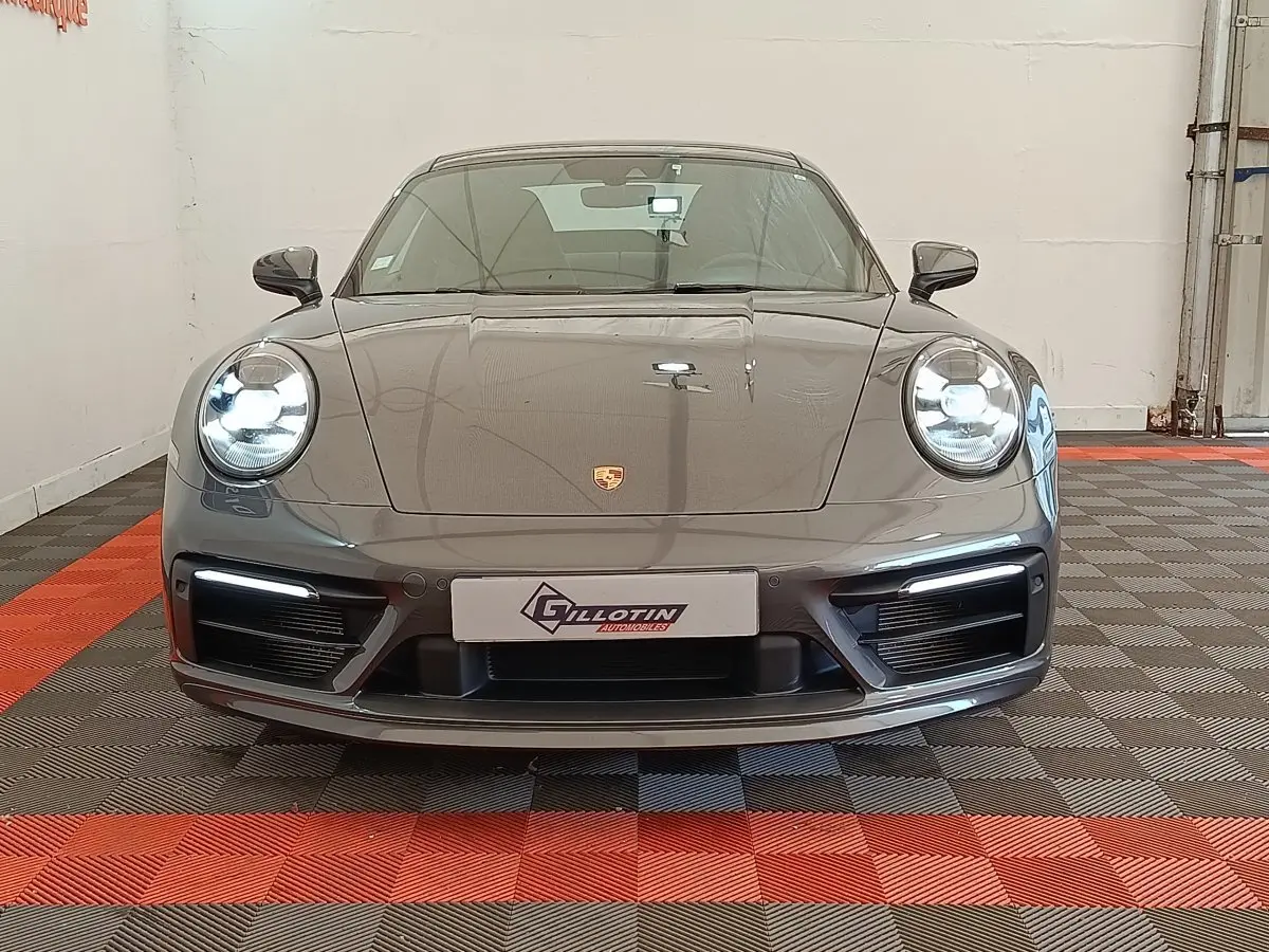 Vue frontale d'une Porsche 911 Carrera 4S Coupé gris foncé avec phares LED allumés en intérieur.