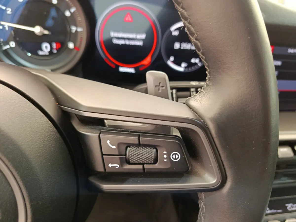 Gros plan sur le volant cuir noir de la Porsche 911 Carrera 4S 2019 avec commandes multifonctions et palettes au volant.