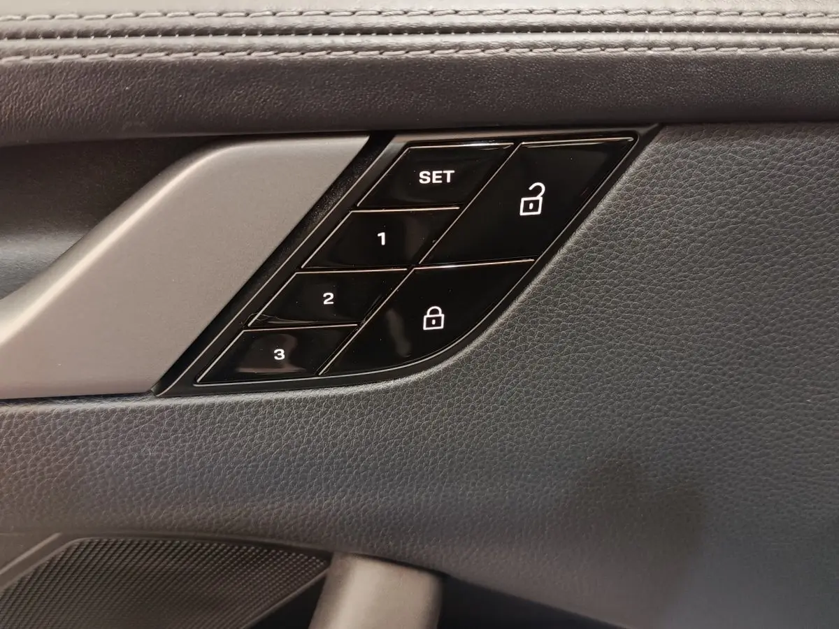 Gros plan sur les commandes de mémoire des sièges et verrouillage sur la porte intérieure côté conducteur, finition cuir noir.