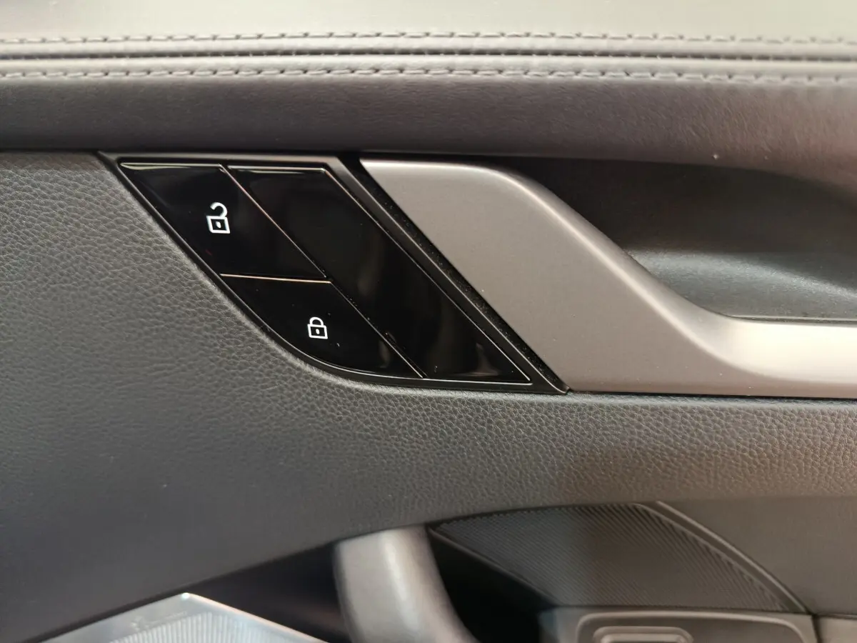 Détail des boutons de verrouillage sur la porte intérieure côté conducteur d’une Porsche 911 Carrera 4S Coupé gris foncé.