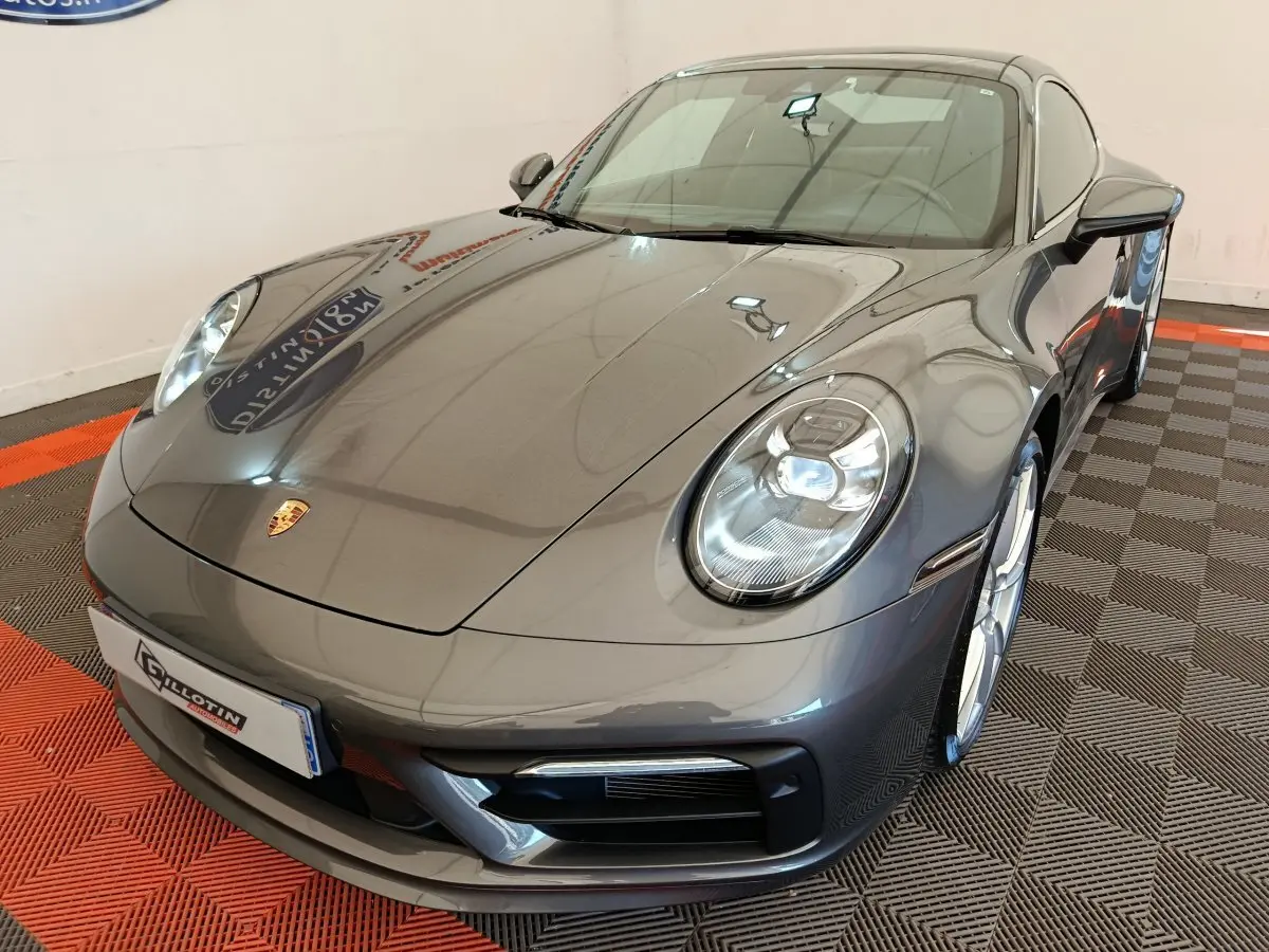 Vue 3/4 avant d'une Porsche 911 Carrera 4S Coupé gris foncé avec phares LED et jantes argentées.