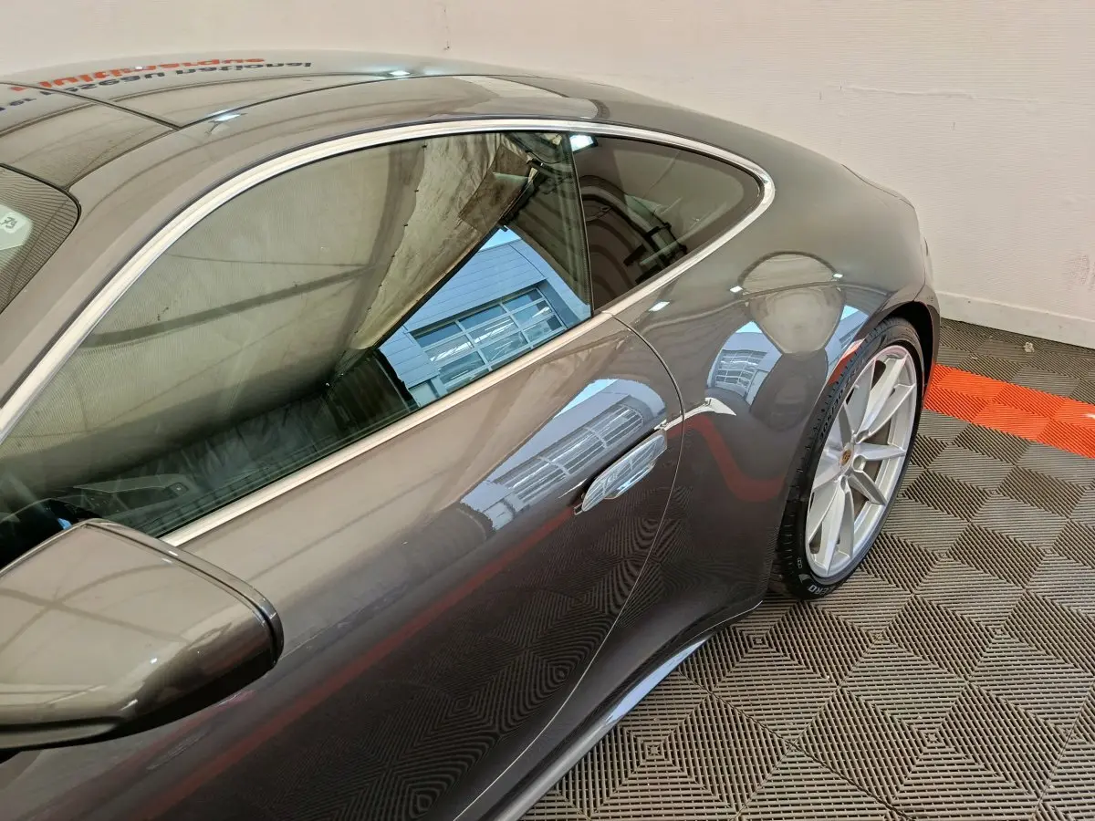 Vue côté droit arrière d'une Porsche 911 Carrera 4S Coupé gris foncé, soulignant la jante alliage et la ligne fluide du toit.