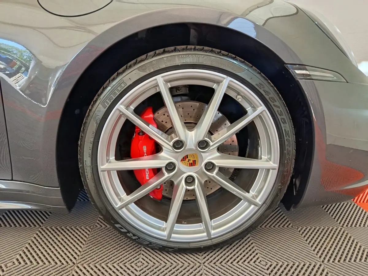 Gros plan sur la roue arrière droite gris foncé d'une Porsche 911 Carrera 4S avec étrier de frein rouge et jante argentée.