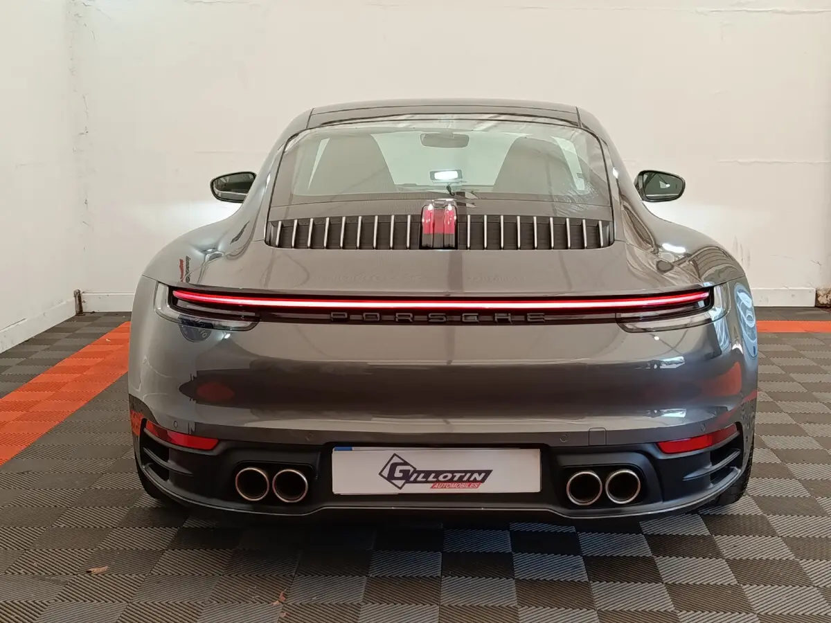 Vue arrière d'une Porsche 911 Carrera 4S Coupé gris foncé avec feux LED continus et quadruple sortie d'échappement.