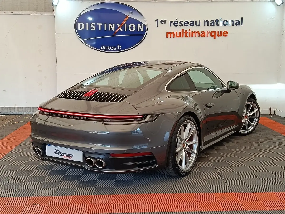 Vue 3/4 arrière droite d'une Porsche 911 Carrera 4S Coupé gris foncé avec feux arrière LED et quadruple sortie d'échappement.