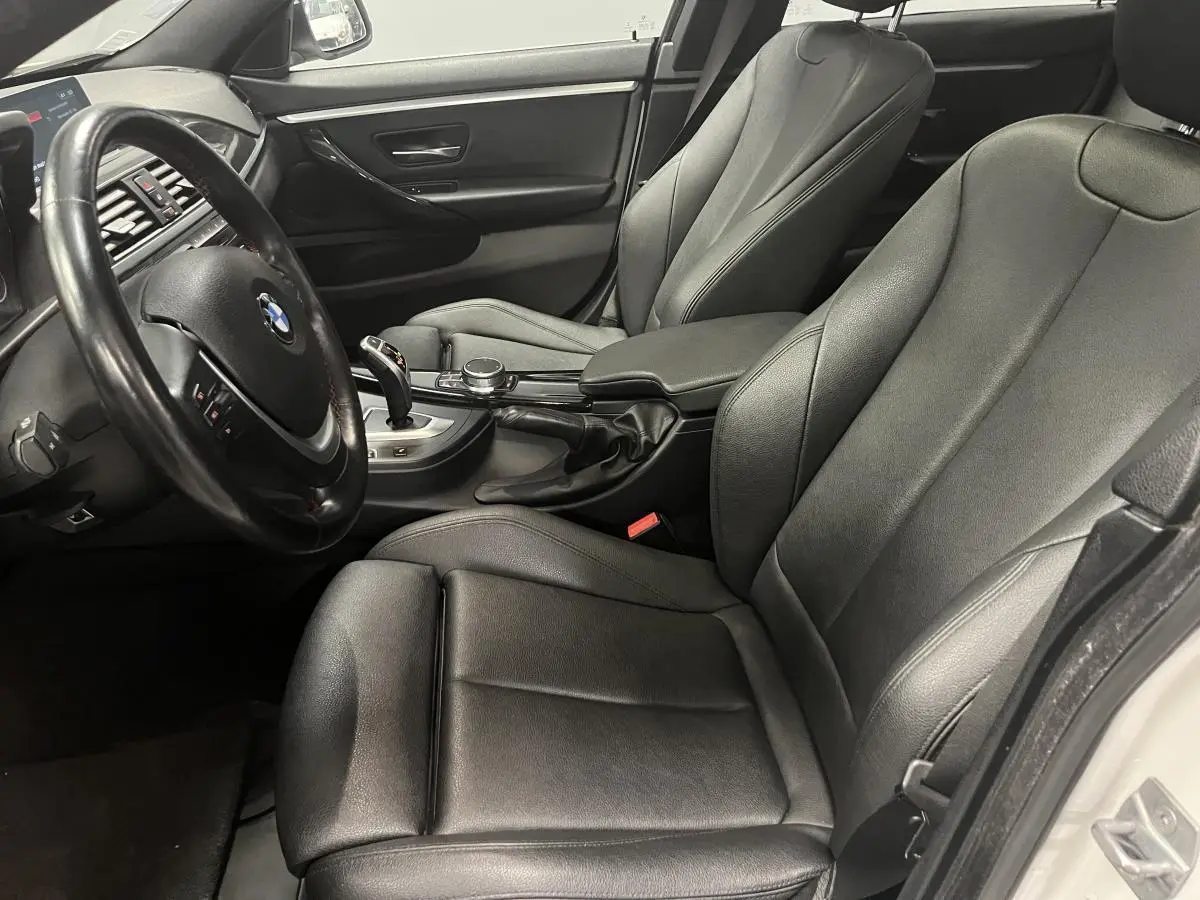 Vue intérieure côté conducteur de la BMW Série 4 430i Gran Coupé 2019 avec sellerie cuir noire et volant multifonctions.
