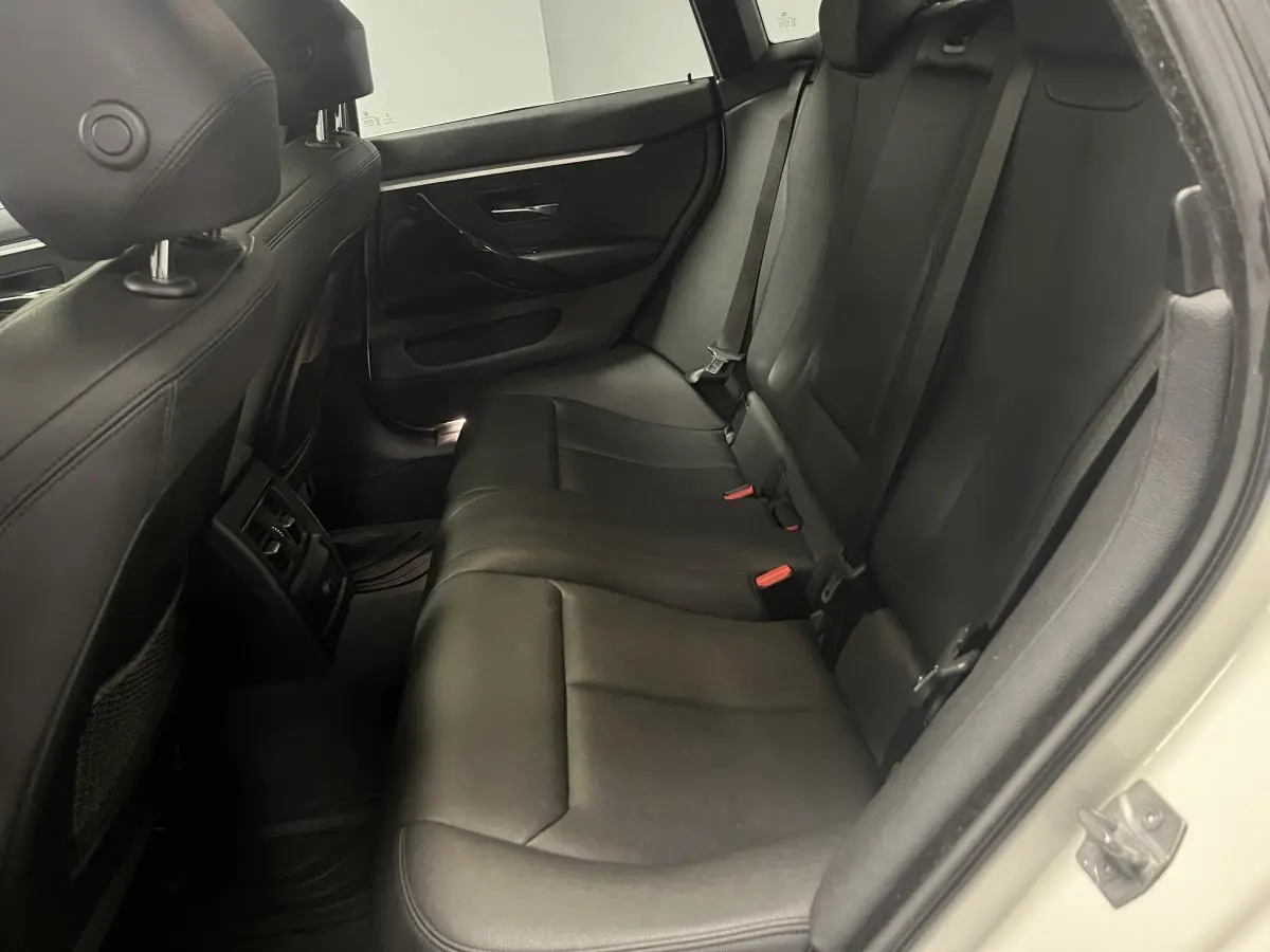 Vue intérieure côté droit des sièges arrière en cuir noir d'une BMW Série 4 Gran Coupé blanc.