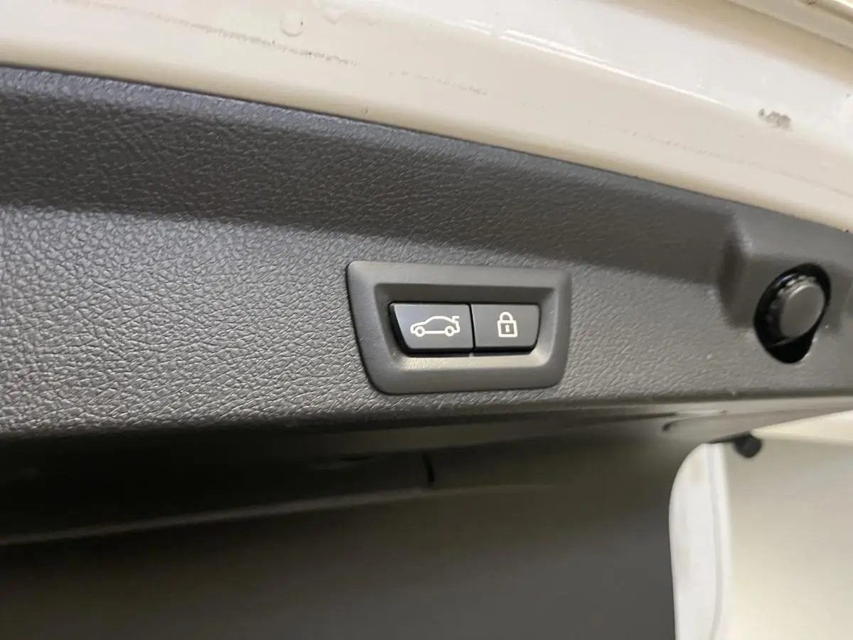 Boutons de fermeture électrique du hayon sur intérieur de coffre d'une BMW Série 4 blanc vue rapprochée.