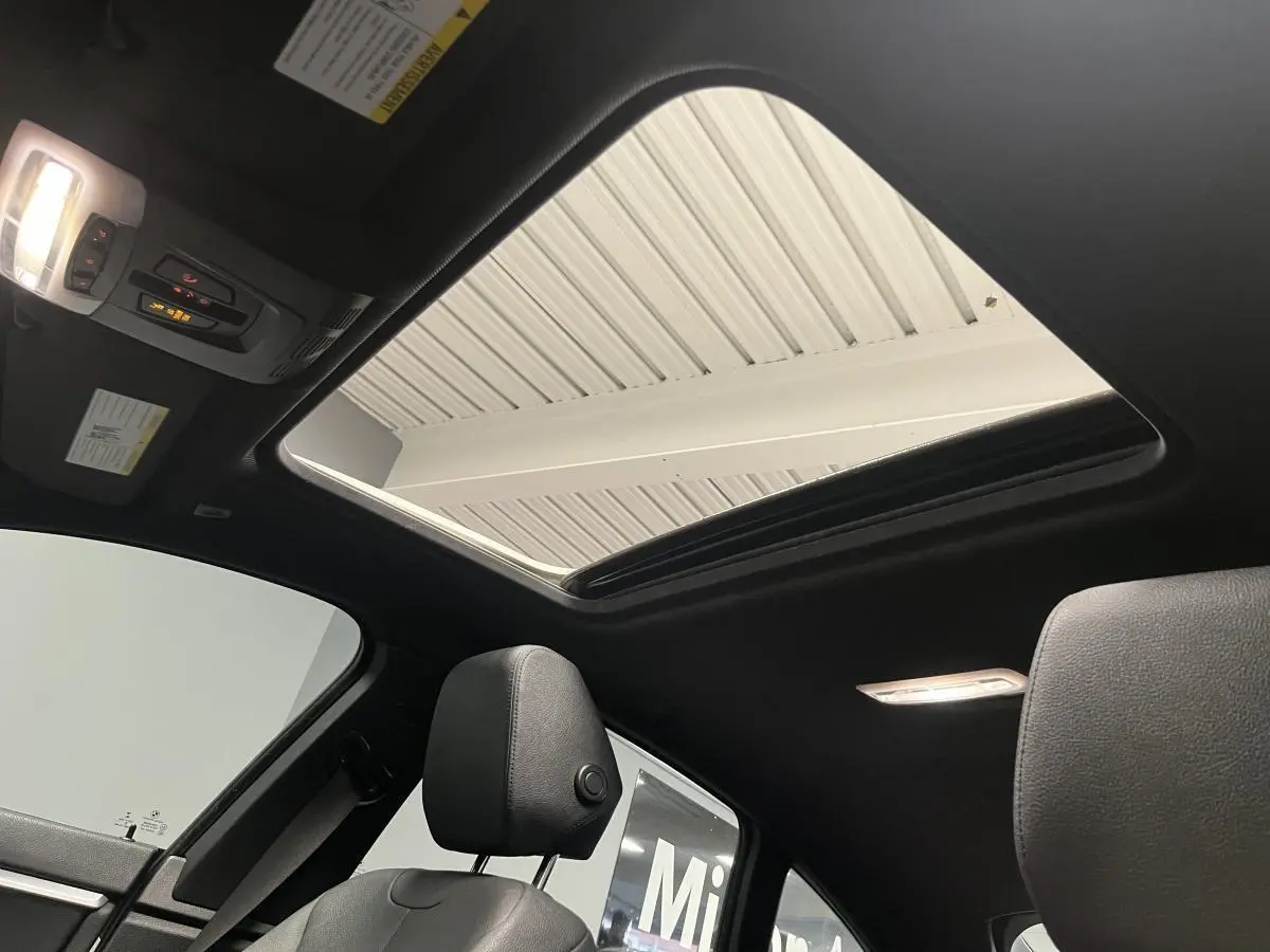 Vue intérieure du toit ouvrant en verre électrique du BMW Série 4 Gran Coupé 430i, avec sellerie cuir noire et éclairage intérieur.
