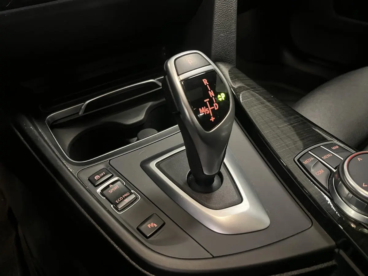 Le levier de vitesses automatique de la BMW Série 4 430i Gran Coupé, entouré de commandes de mode de conduite et d'un habillage noir brillant.