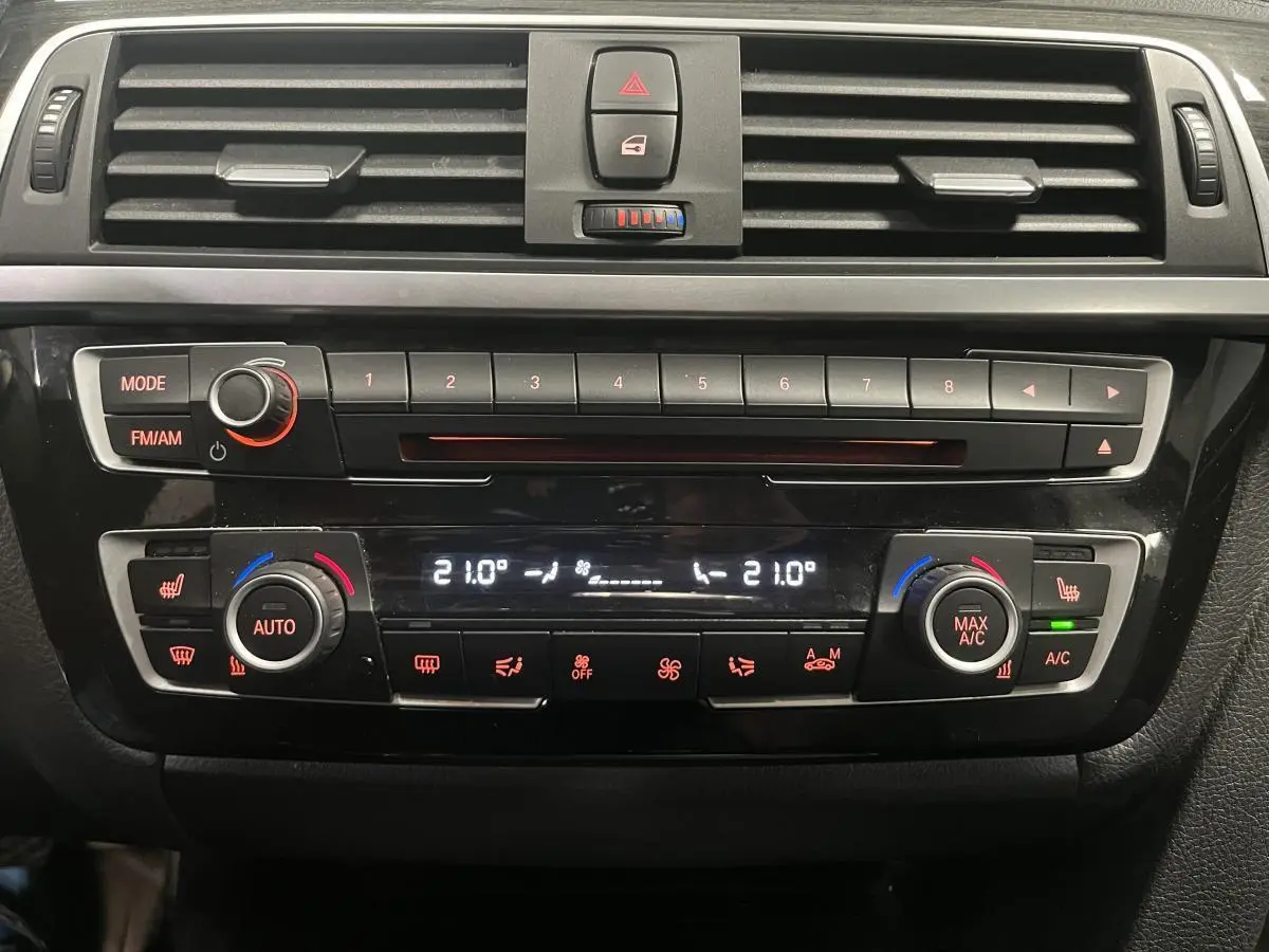 Vue rapprochée de la console centrale noire de la BMW Série 4 430i avec commandes climatisation et radio.