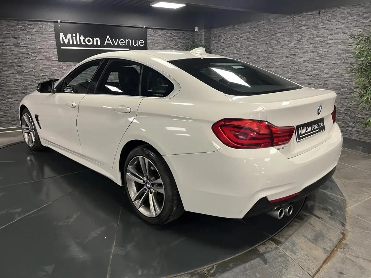 BMW Série 4 Gran Coupé blanc vue 3/4 arrière droit avec jantes alliage 18 pouces et double sortie d’échappement.