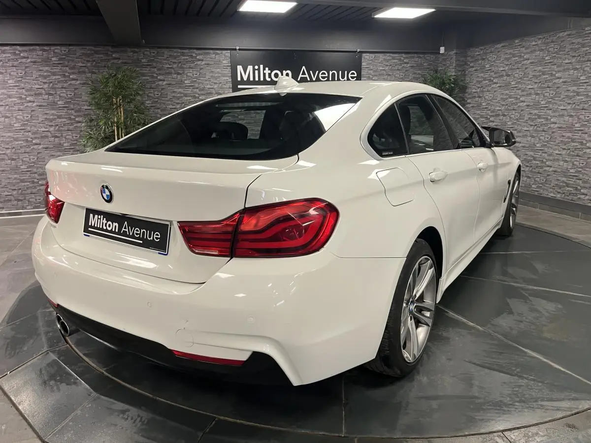 BMW Série 4 430i Gran Coupé blanc vue 3/4 arrière droit avec jantes alliage 18'' et feux arrière LED rouges.
