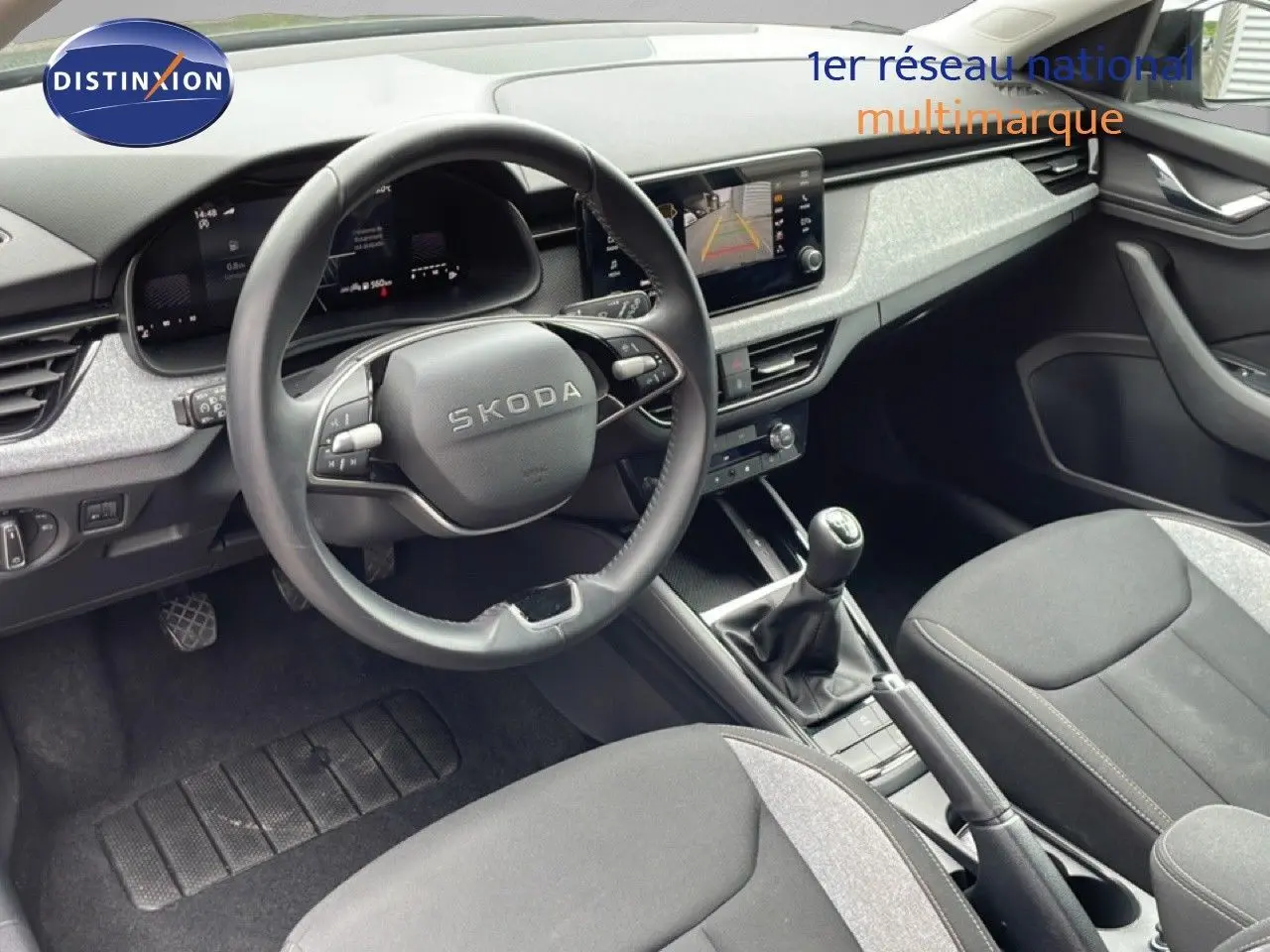 Intérieur avant de la Skoda Scala 2025, vue côté conducteur, volant cuir, tableau de bord gris et écran tactile.