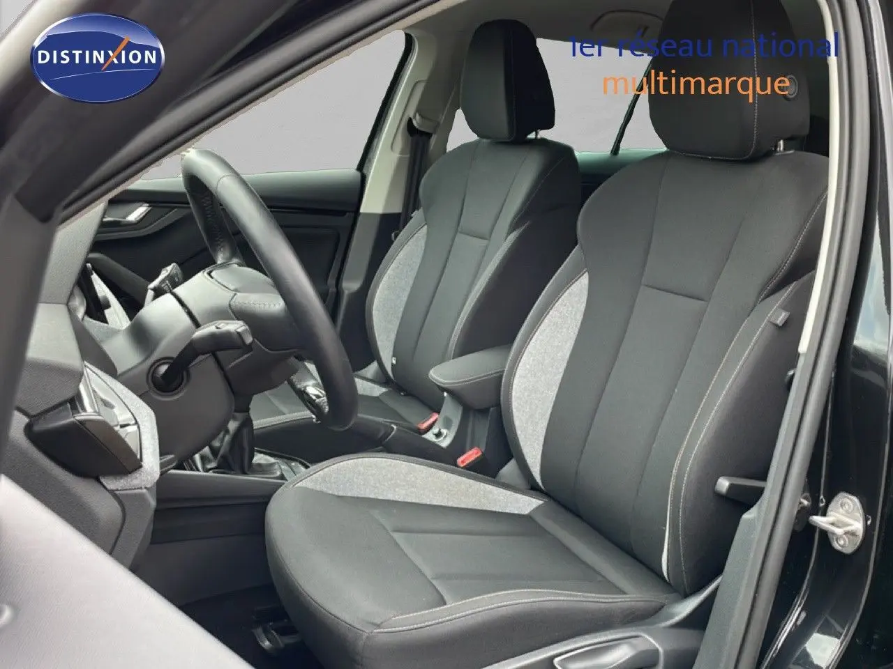 Vue intérieure côté conducteur montrant les sièges tissu gris et noir d'une Skoda Scala 2025 noir magique métal.