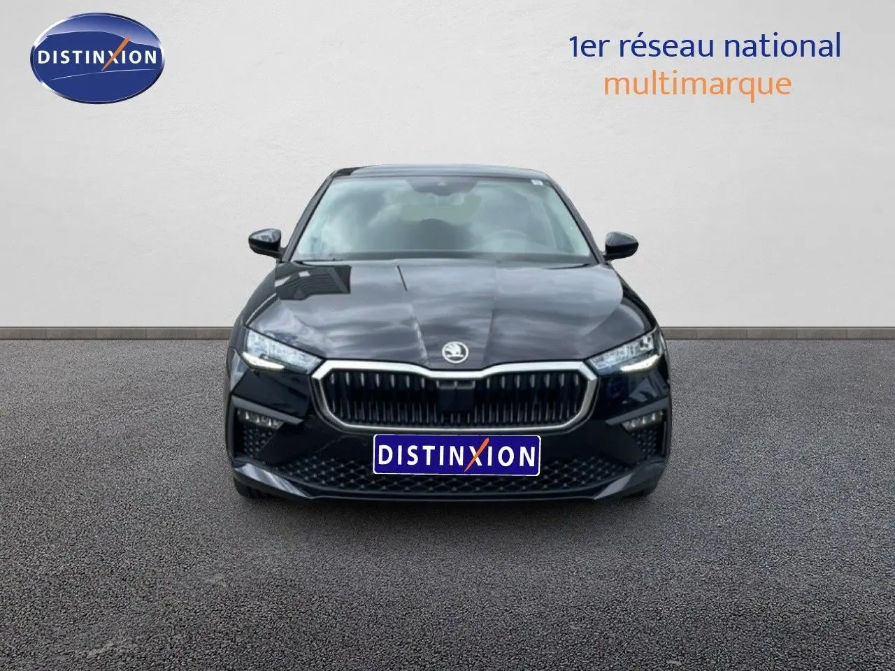 Vue frontale d'une Skoda Scala noire métallisée avec calandre chromée et phares LED allumés.