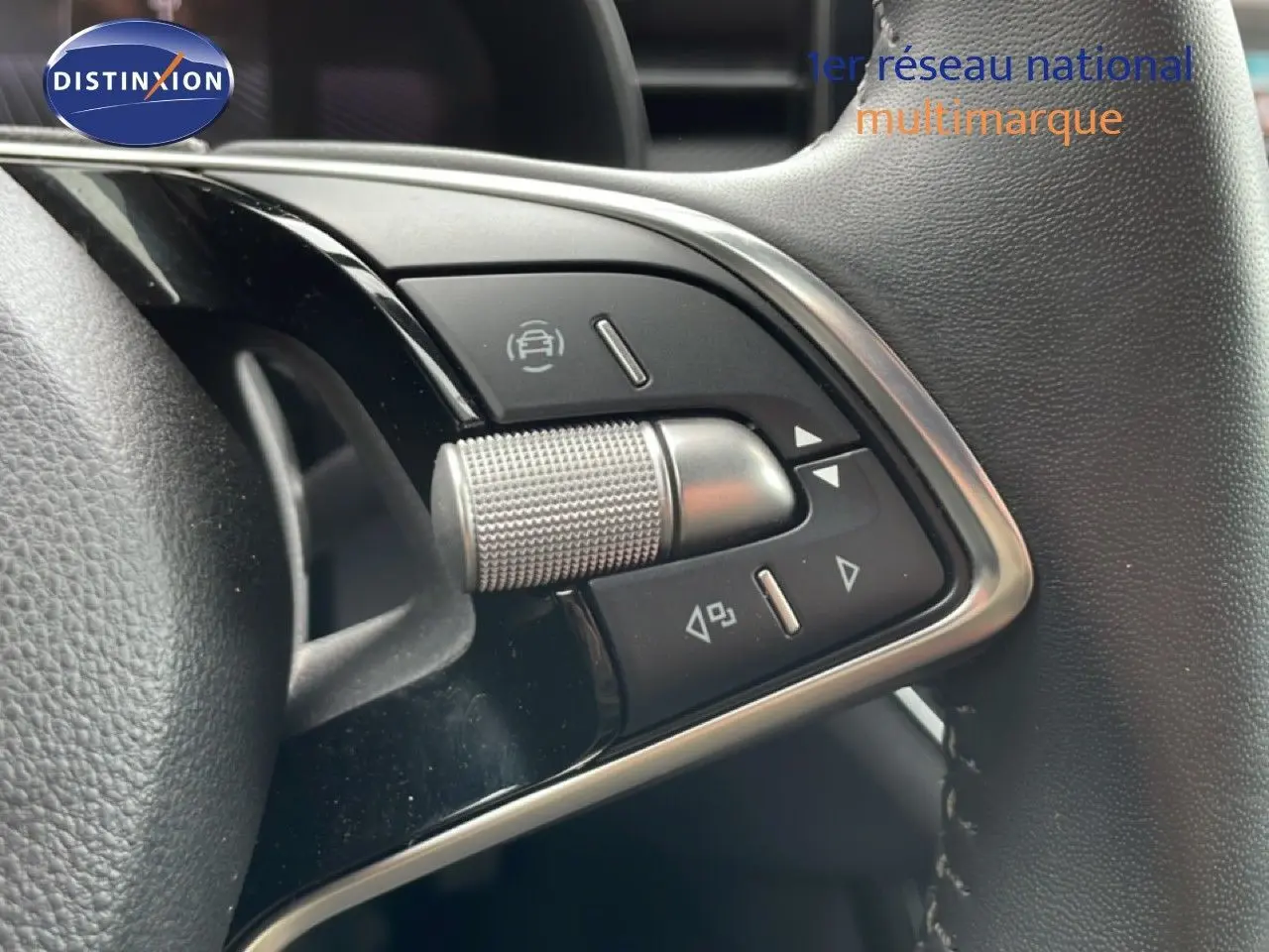 Gros plan sur les commandes multifonctions en métal brossé du volant cuir noir de la Skoda Scala 2025.