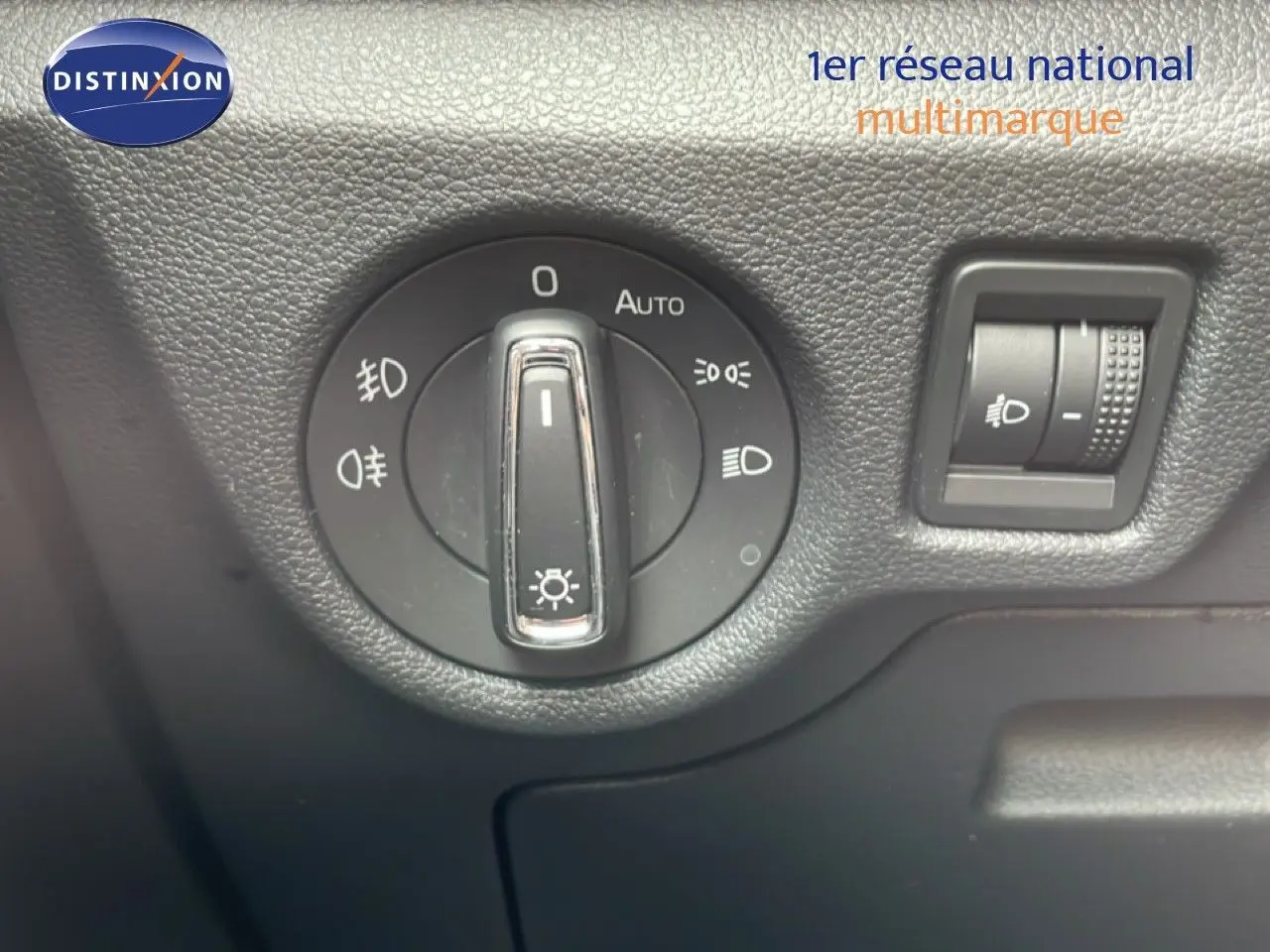 Gros plan sur la molette de réglage des phares et le variateur d'intensité lumineuse dans l'habitacle d'une Skoda Scala noire.
