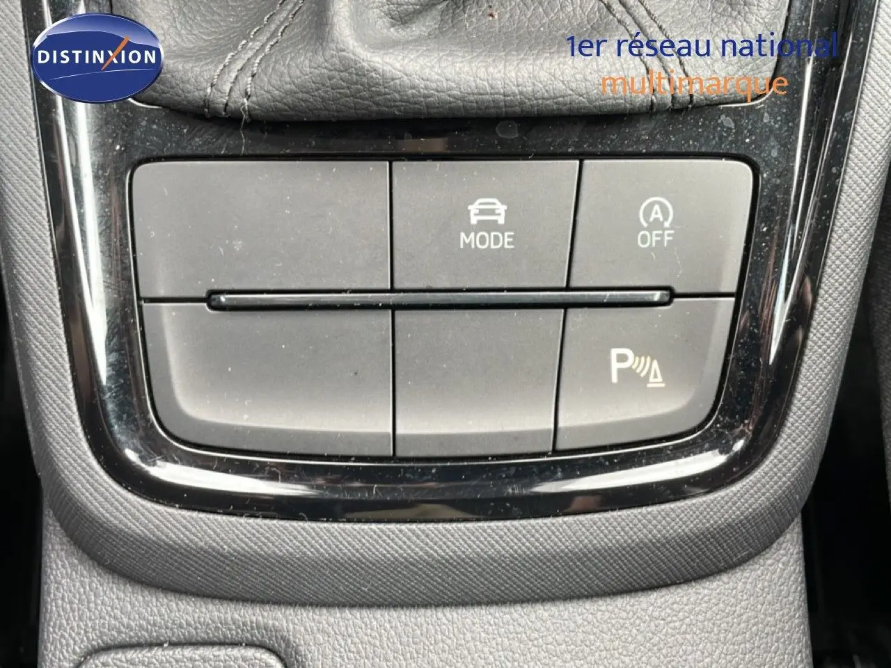 Gros plan sur les boutons de commande du mode de conduite et assistance au stationnement d'une Skoda Scala noire.