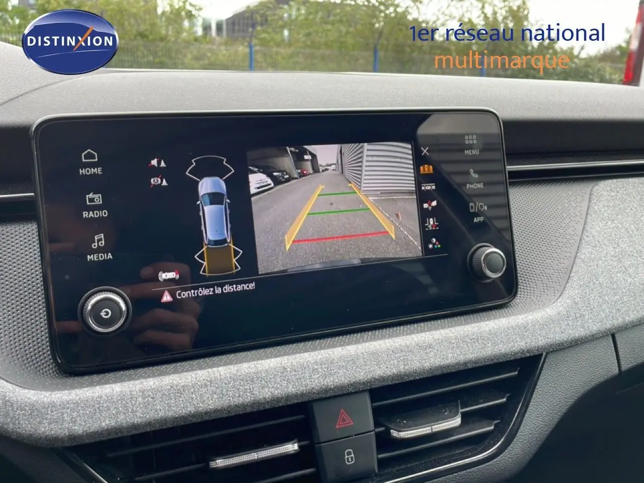 Écran central affichant la caméra de recul et l'alerte de distance dans un Skoda Scala noir Magic Metal, vue intérieure.
