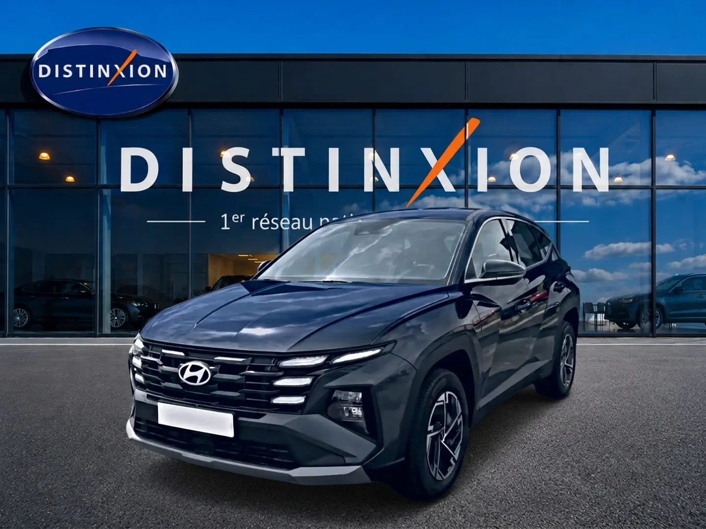 Hyundai Tucson 1.6 t-gdi 239 hybride gris ecotronique vu en 3/4 avant devant un bâtiment vitré Distinxion.