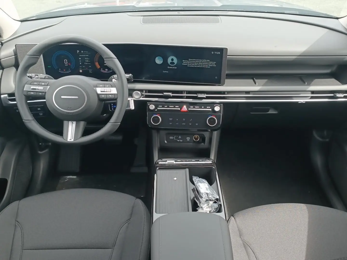 Vue intérieure avant du Hyundai Tucson 2026, tableau de bord moderne avec écran large et volant multifonction noir.