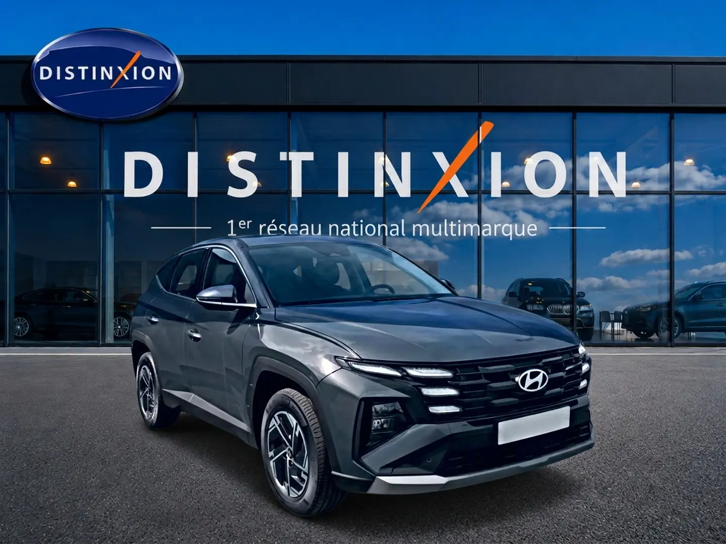 Hyundai Tucson gris ecotronique en 3/4 avant droit, avec calandre noire et jantes alliage 17 pouces visibles.