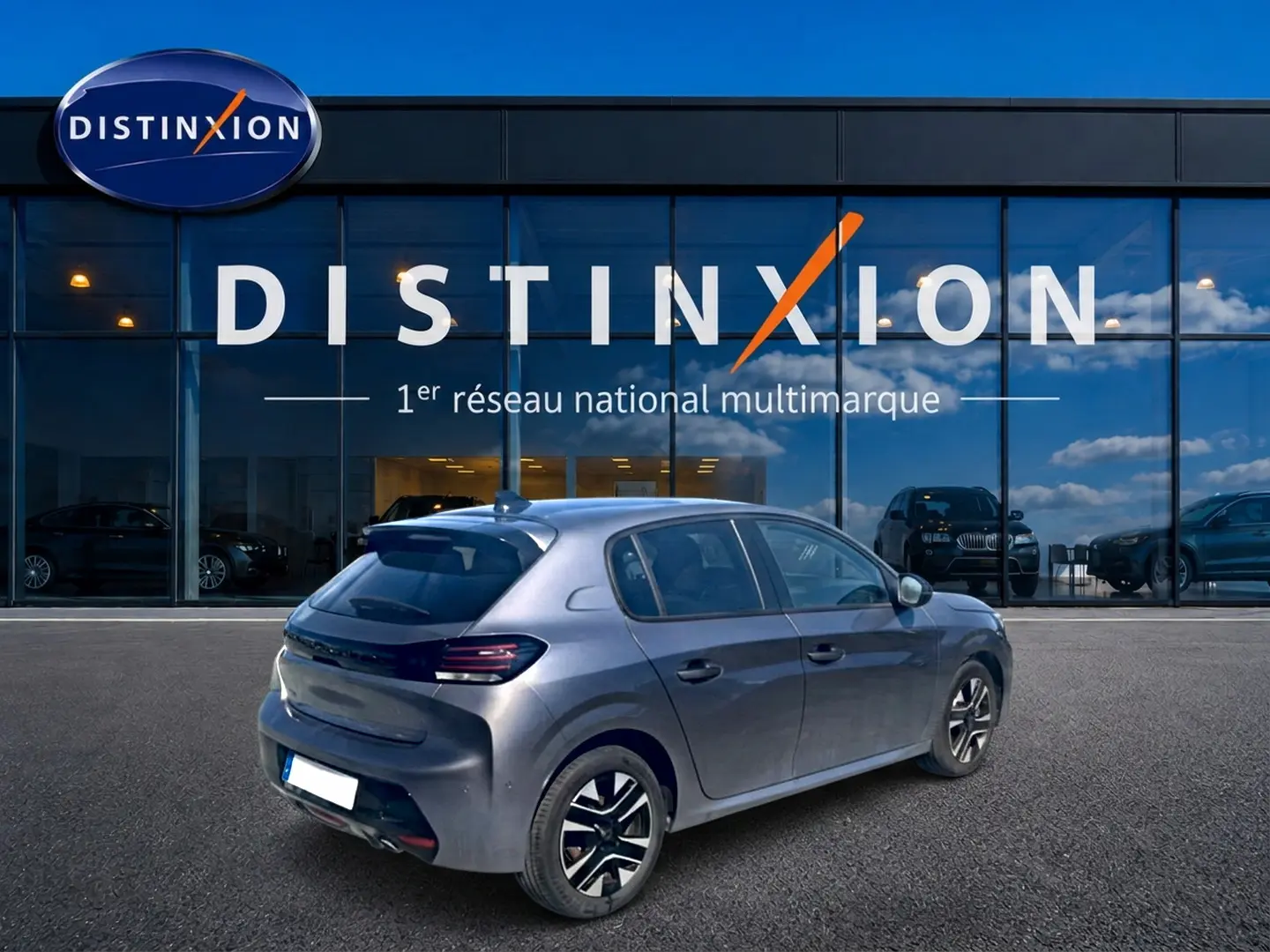 Peugeot 208 1.2 100 Allure gris Artense vue 3/4 arrière droit devant un showroom Distinxion.