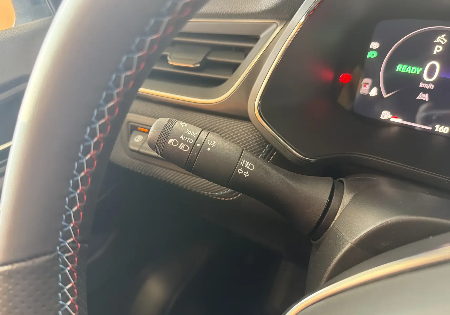 Gros plan sur la commande des feux et clignotants à gauche du volant du Renault Captur E-Tech 160 Esprit Alpine gris Rafale.