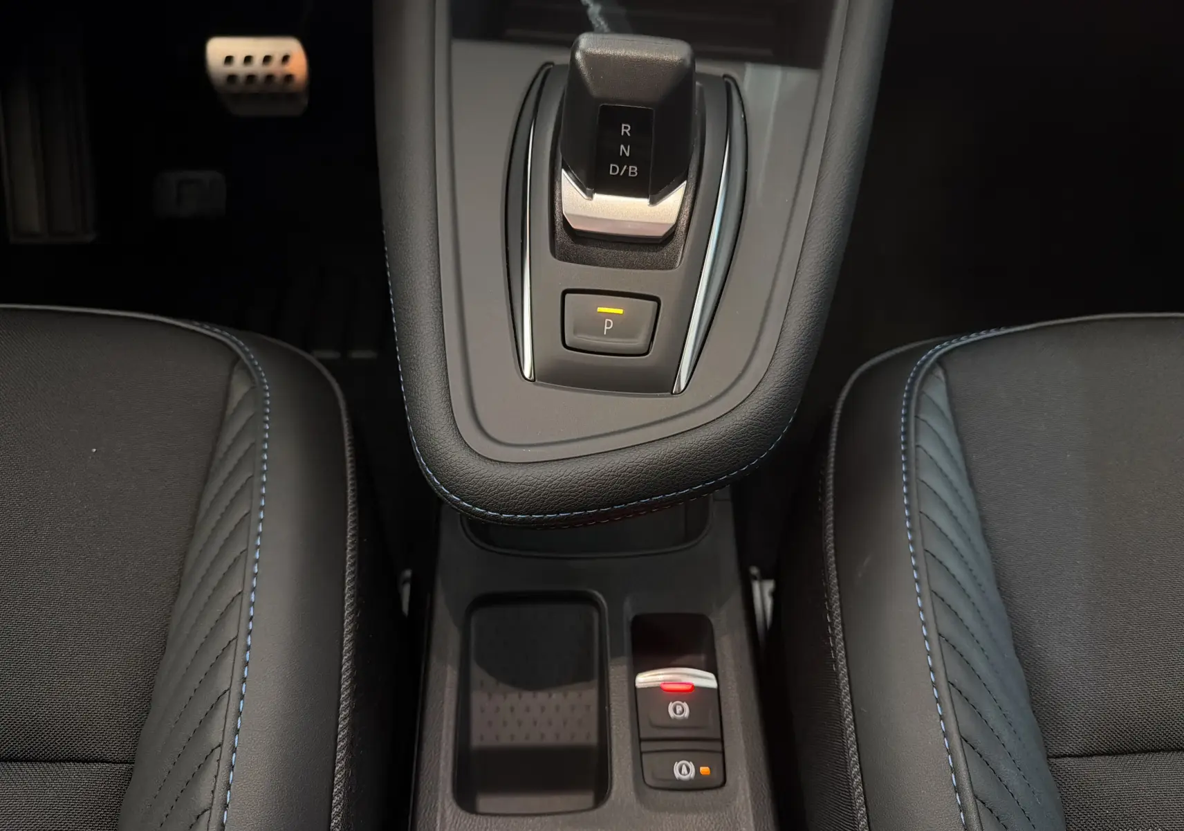 Vue rapprochée de la console centrale du Renault Captur E-Tech 160 Esprit Alpine avec levier de vitesse et sellerie noire à surpiqûres bleues.