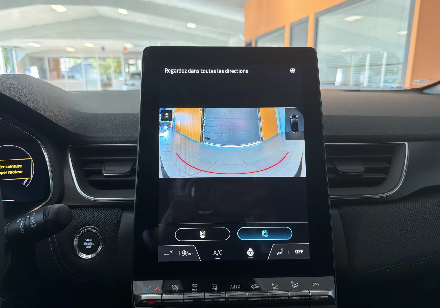 Vue intérieure centrée sur l'écran tactile affichant la caméra de recul du Renault Captur E-Tech gris Rafale, avec tableau de bord et console visibles.