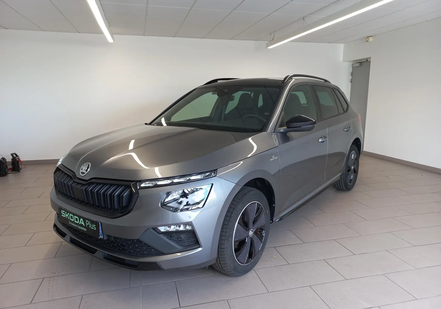 Vue 3/4 avant droite du Skoda Kamiq Monte Carlo 2024 gris graphite avec calandre noire et jantes spécifiques.