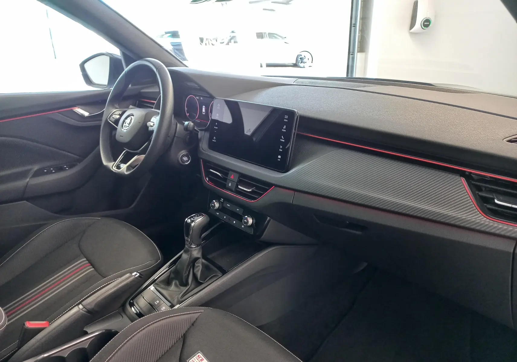 Vue intérieure côté conducteur du Skoda Kamiq 2024 Monte Carlo, avec tableau de bord noir et touches rouges décoratives.