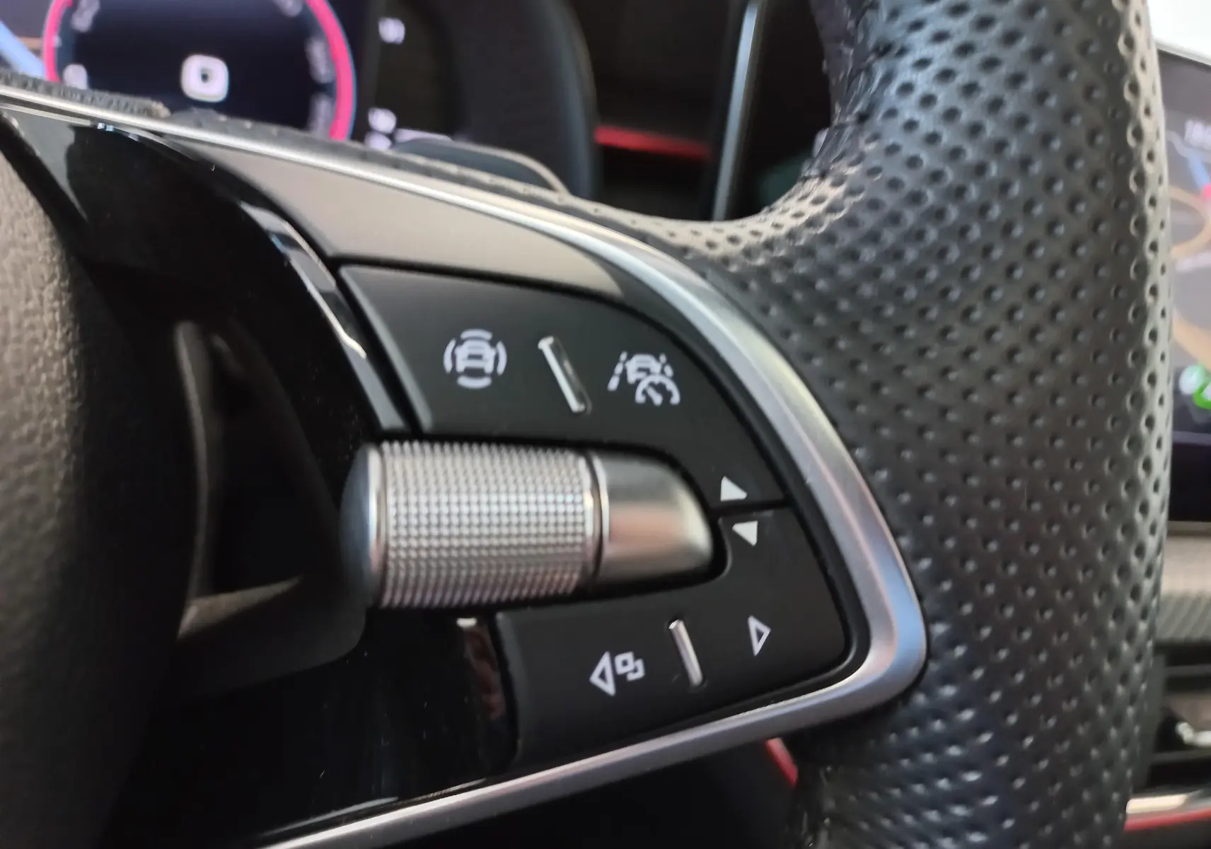 Gros plan sur les commandes du volant perforé du Skoda Kamiq Monte Carlo gris graphite, avec molette métallique et boutons multifonctions.