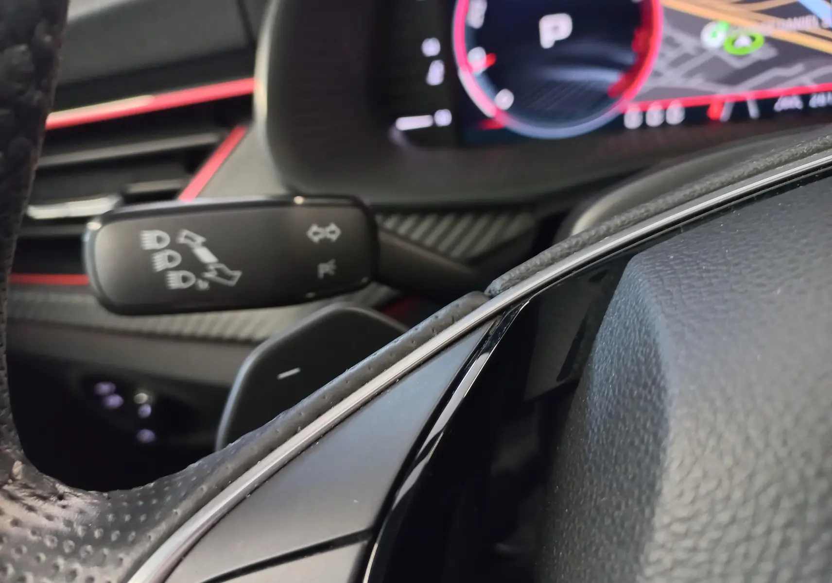 Détail intérieur du volant et commodo gauche du Skoda Kamiq 2024 Monte Carlo avec éclairage rouge et finition carbone.