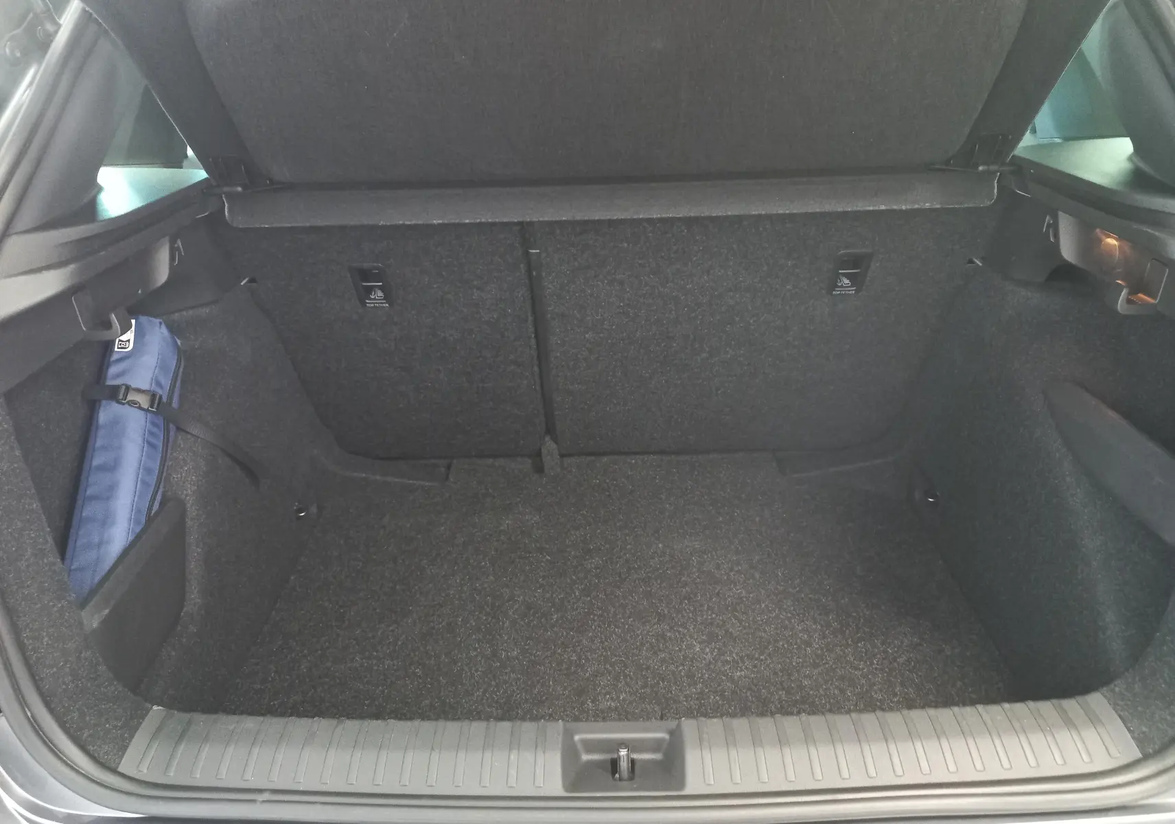 Coffre ouvert vu de l'arrière du Skoda Kamiq 1.5 TSI Monte Carlo gris graphite, montrant un espace de rangement propre.