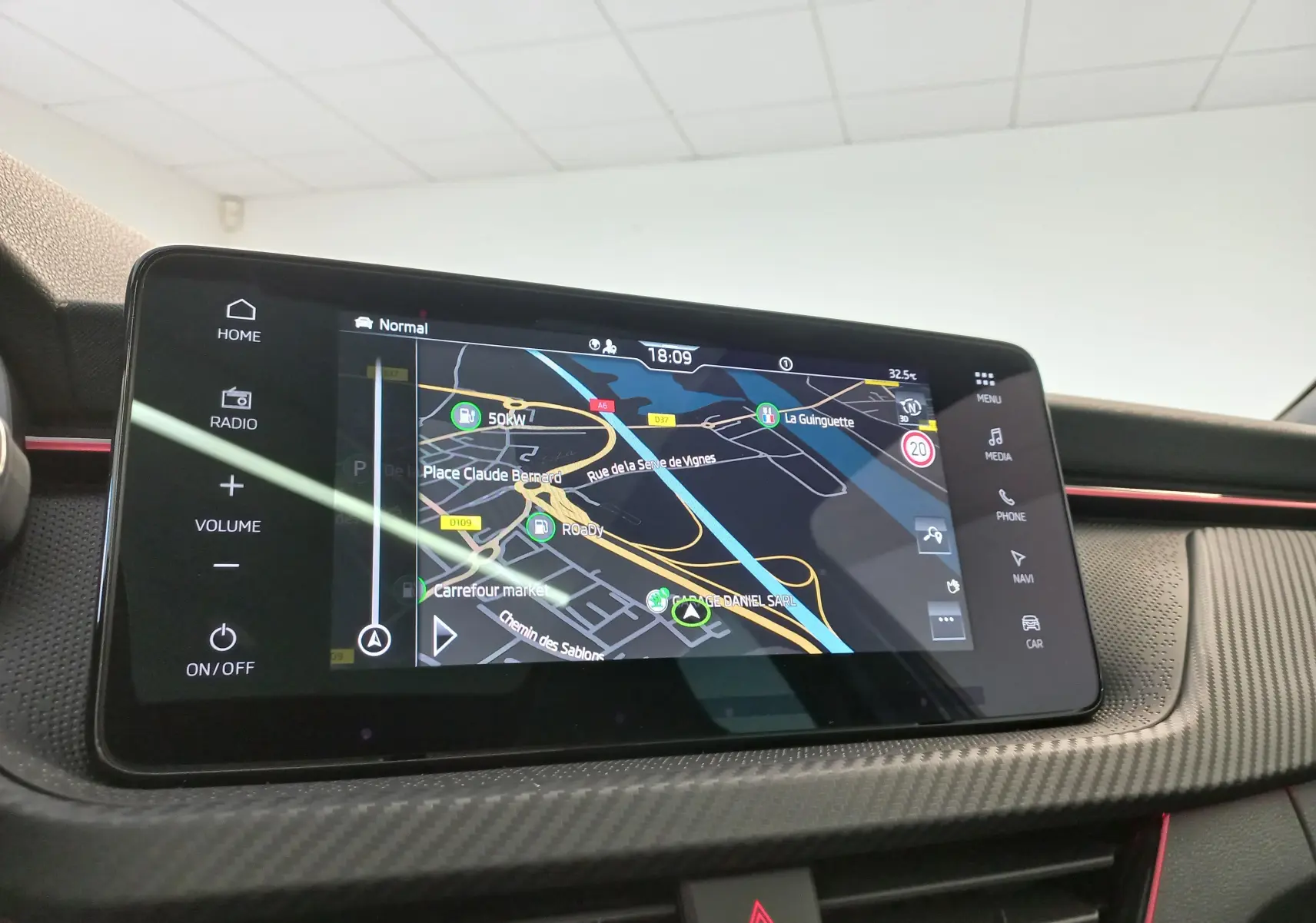 Écran tactile central du Skoda Kamiq 2024 Monte Carlo en gros plan, affichant la navigation GPS sur fond noir.