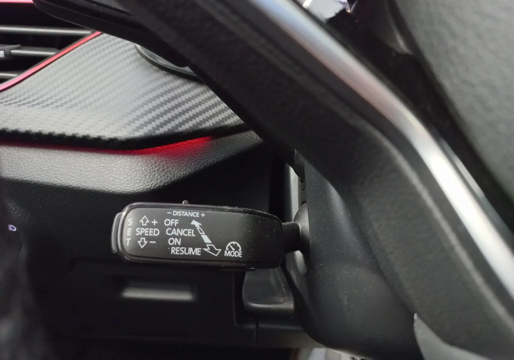 Gros plan sur la commande de régulateur de vitesse du Skoda Kamiq 1.5 TSI 150 DSG7 Monte Carlo, intérieur noir avec insert carbone.