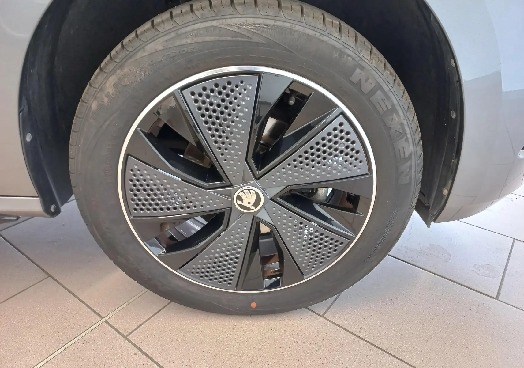 Gros plan sur la roue avant droite du Skoda Kamiq 2024 gris graphite, mettant en valeur la jante Monte Carlo au design perforé noir et gris.