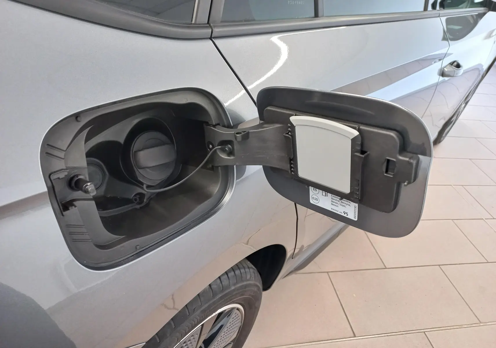 Détail de la trappe à carburant ouverte côté gauche d’un Skoda Kamiq gris graphite 2024, vue latérale.