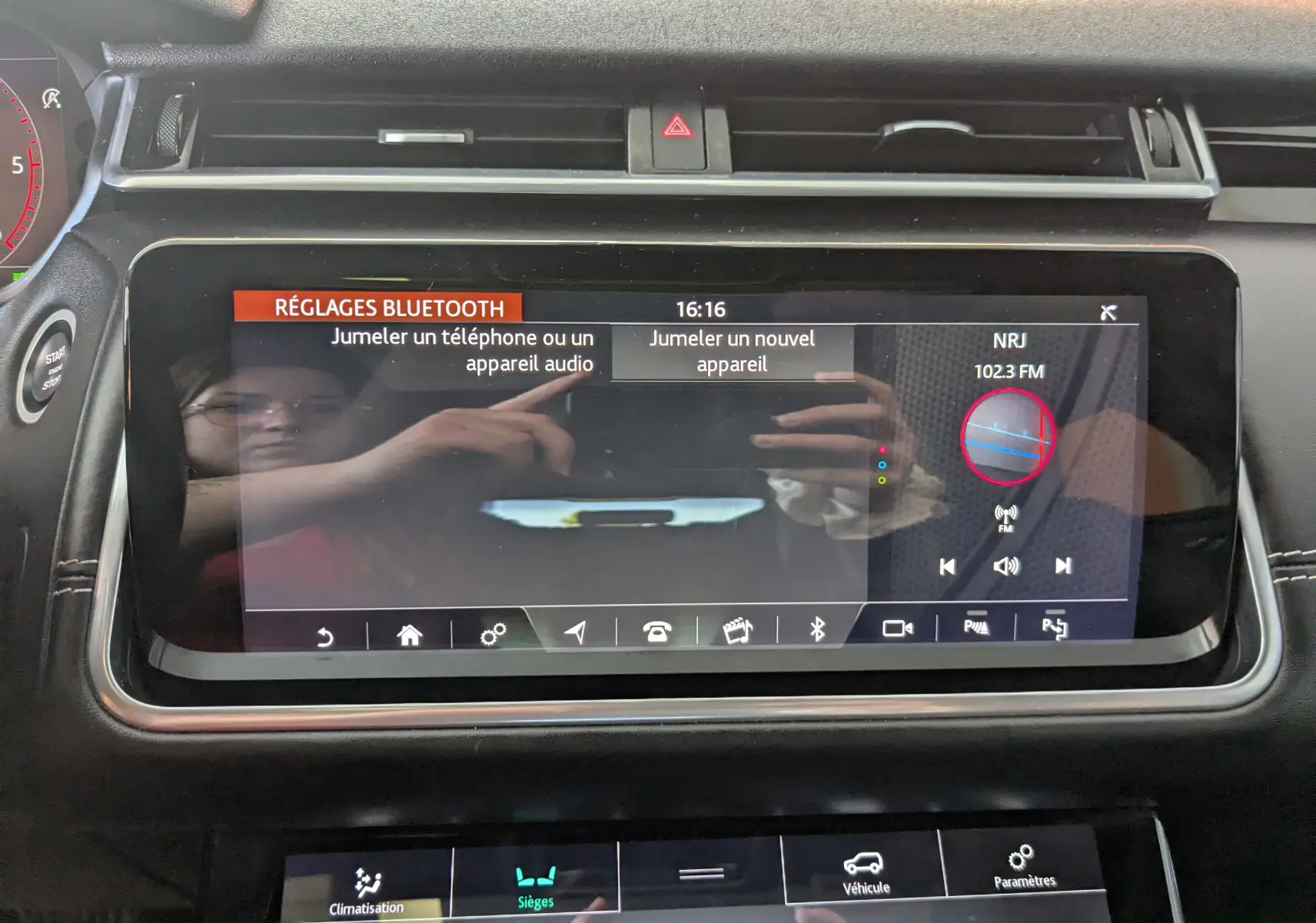 Écran tactile central du Range Rover Velar noir 2020 affichant les réglages Bluetooth et la radio NRJ.