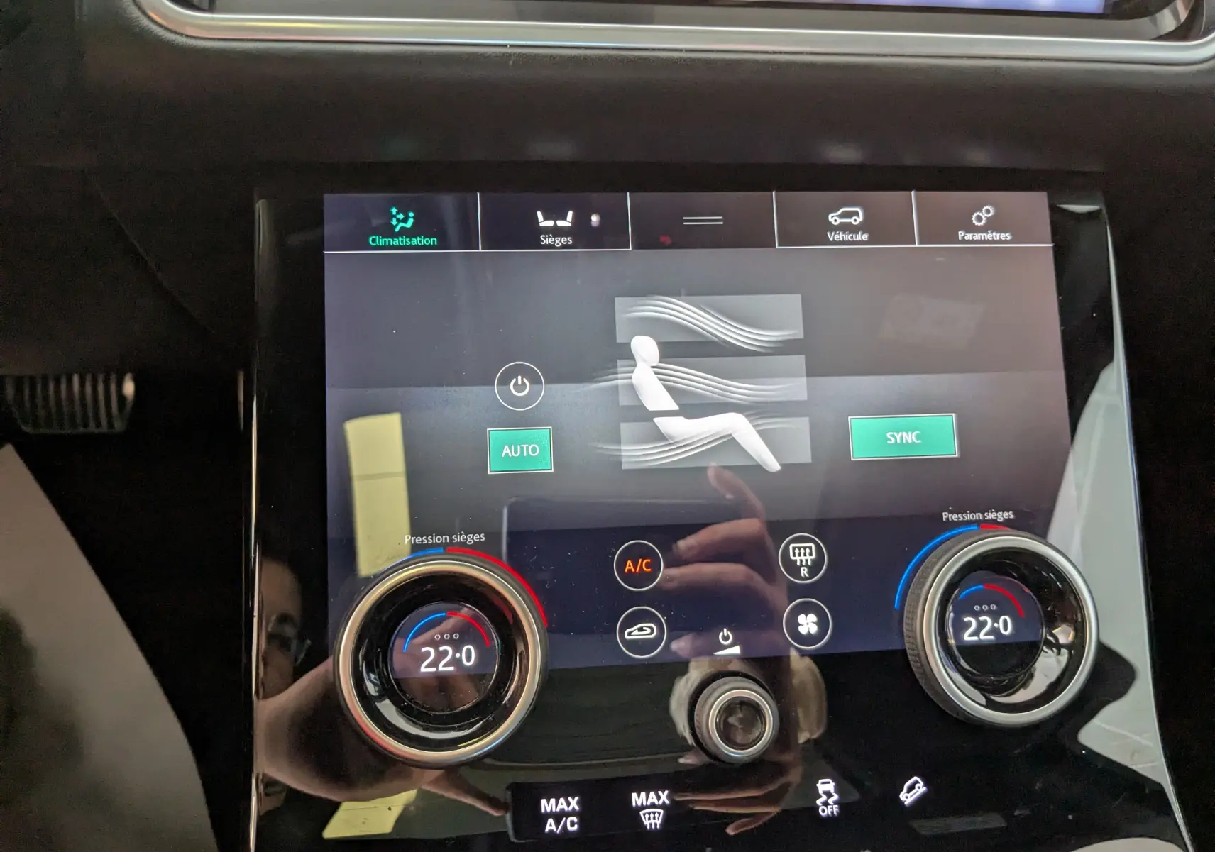 Écran tactile de la climatisation du Range Rover Velar noir, affichant 22°C avec réglages sièges et ventilation.