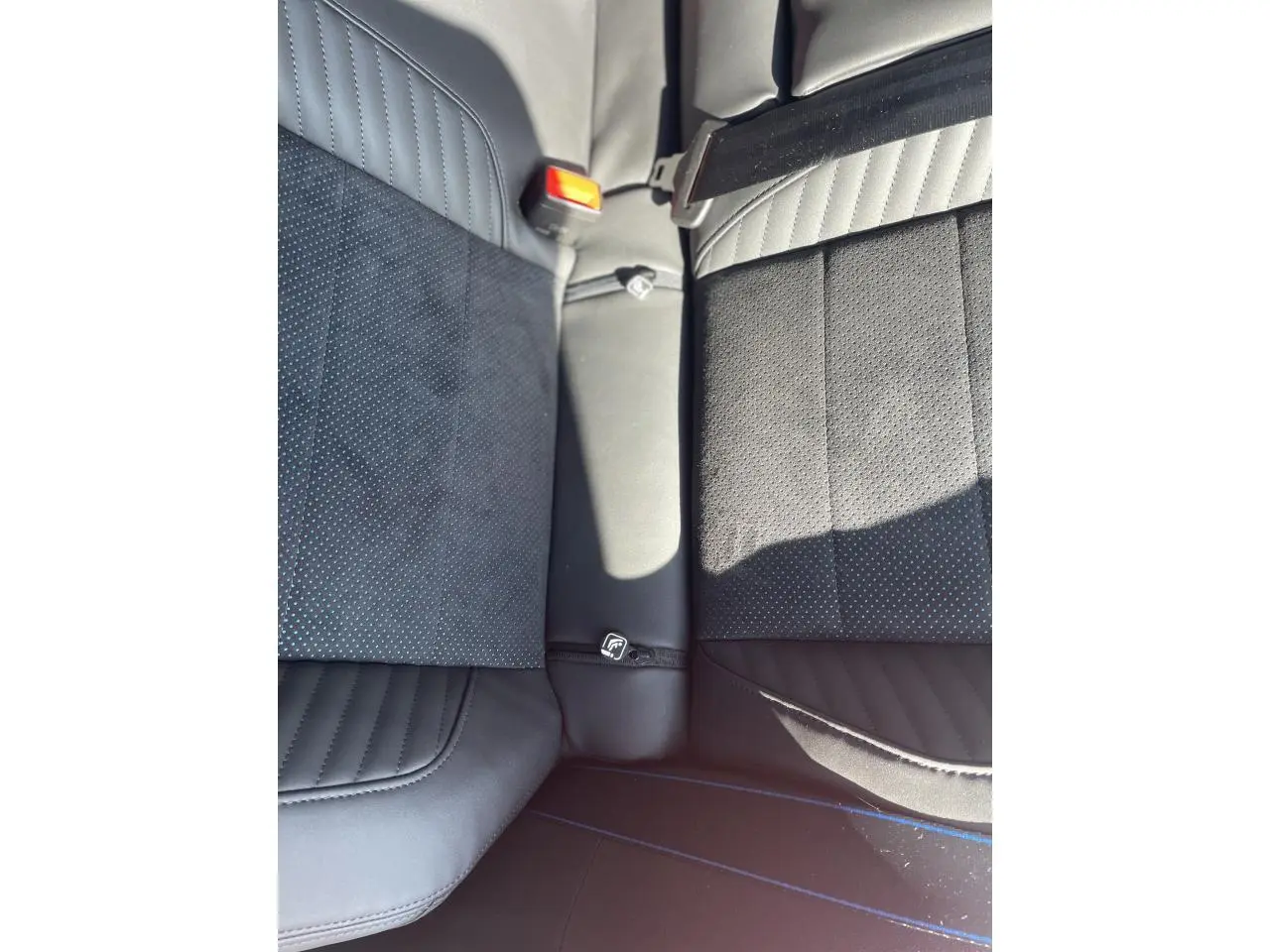 Gros plan sur la banquette arrière noire avec surpiqûres bleues et ceinture de sécurité rouge de la Renault Rafale Esprit Alpine 2025