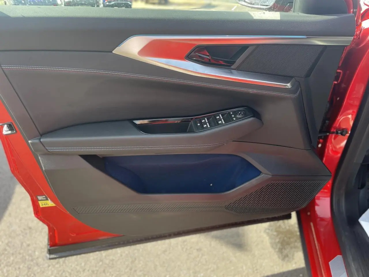 Gros plan sur la porte avant gauche rouge du Renault Rafale Esprit Alpine, avec commandes de vitres et surpiqûres blanches.